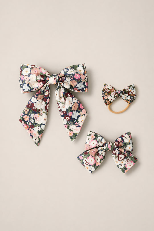 Three floral-patterned hair accessories from Ivy City Co’s Hair Bows in Midnight Garden collection—a large bow with long tails, a medium-sized bow, and a small elastic hair tie—are displayed on a neutral background.