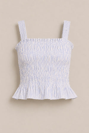 The Ivy City Co Harley Top in Blue & White Pinstripe features smocking, wide shoulder straps, and a ruffled hem. This sleeveless top is shown against a plain beige background.
