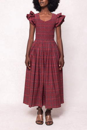 Woman wearing a red plaid dress with ruffled sleeves on a white background