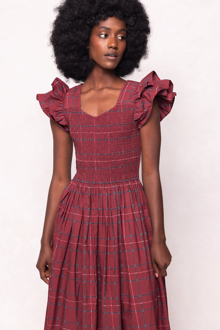 Woman wearing a red plaid dress with ruffled sleeves against a white background