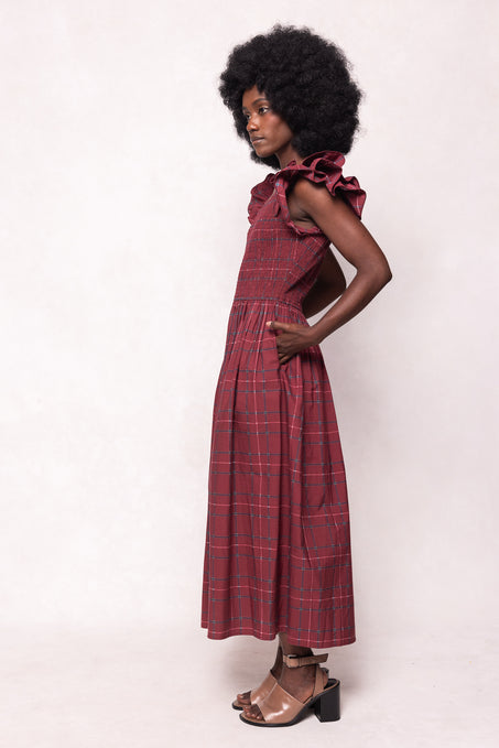 Woman wearing a red plaid dress with ruffled sleeves against a white background