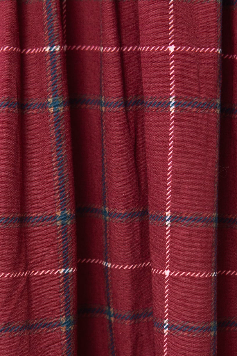 A close-up of the Hattie Dress in Burgundy Plaid by Ivy City Co highlights its white, blue, and black plaid fabric and gathered seam detail—perfect for a stylish midi-length look.
