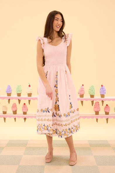 Woman wearing a pink floral dress standing in front of a pastel ice cream cone display.