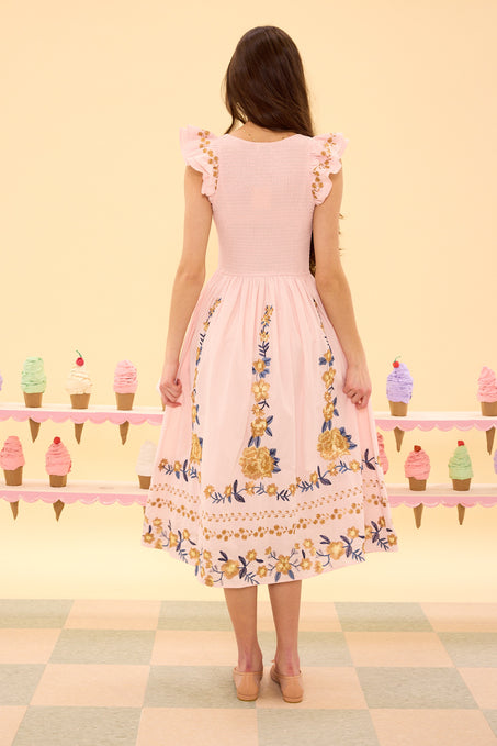 Woman wearing a pink floral dress standing in front of a colorful ice cream display.