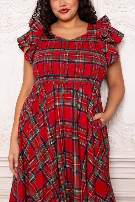 Woman wearing a red plaid dress with ruffled shoulders against a white background