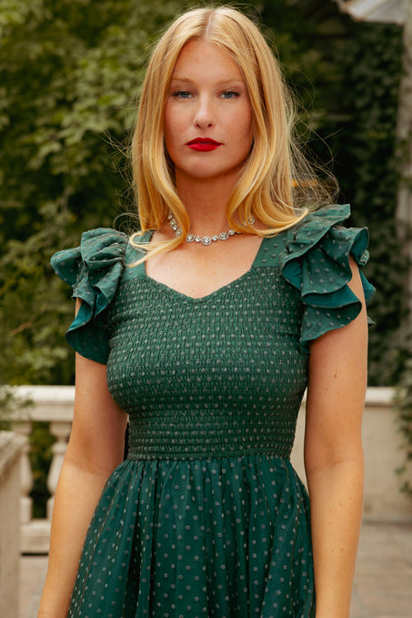 Woman wearing a green dress with ruffled sleeves outdoors