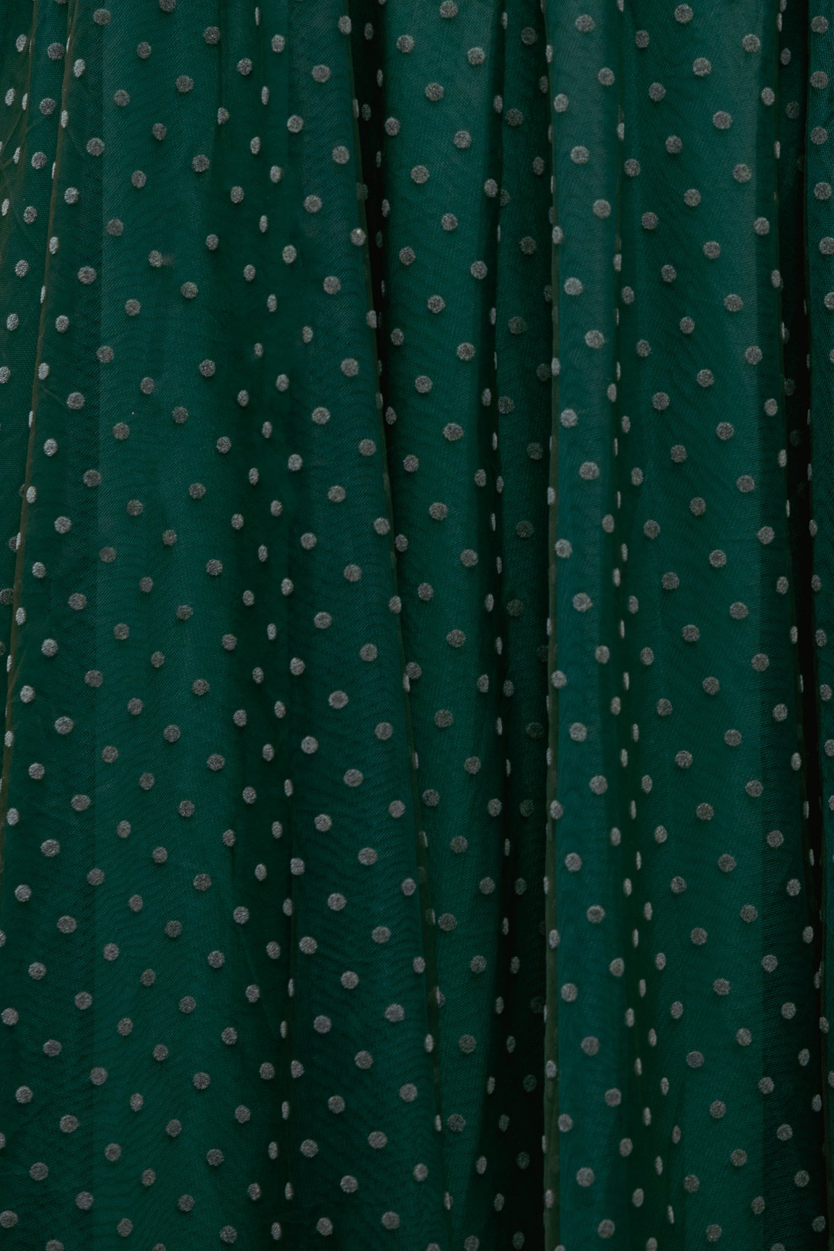 Dark green fabric with small white polka dots