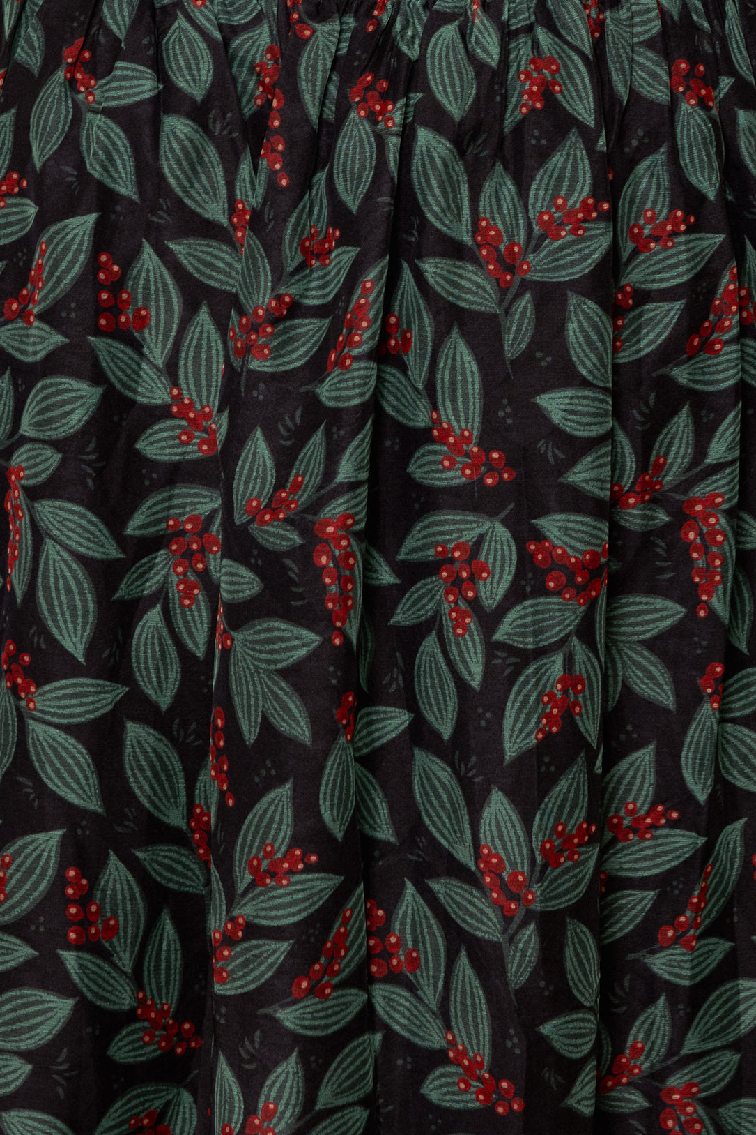 Close-up of fabric with red berry and green leaf pattern on black background