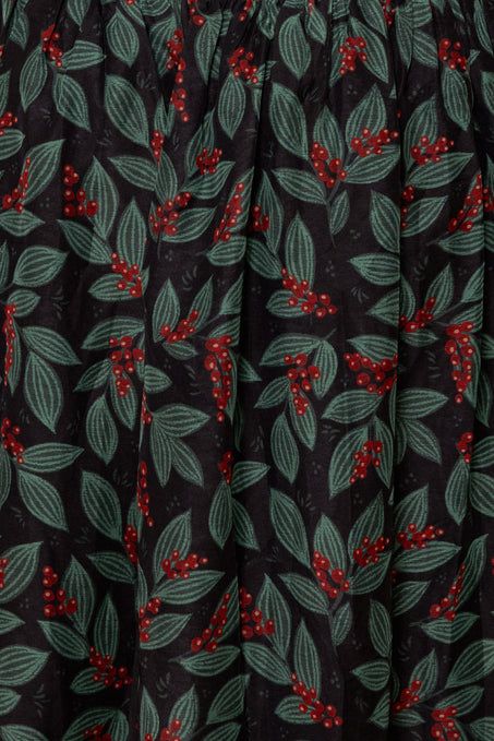 Close-up of fabric with red berry and green leaf pattern on black background