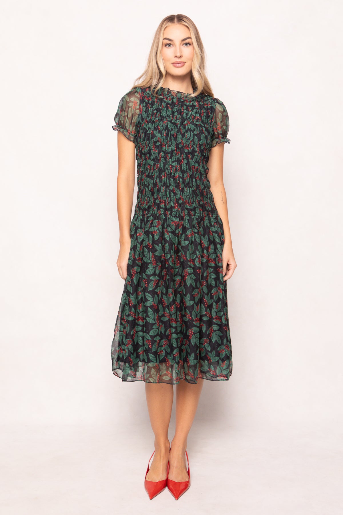 model in green holly berry dress on a white backdrop