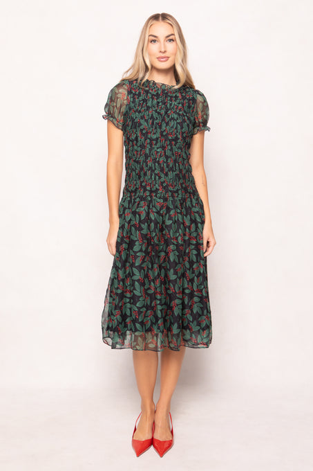 model in green holly berry dress on a white backdrop