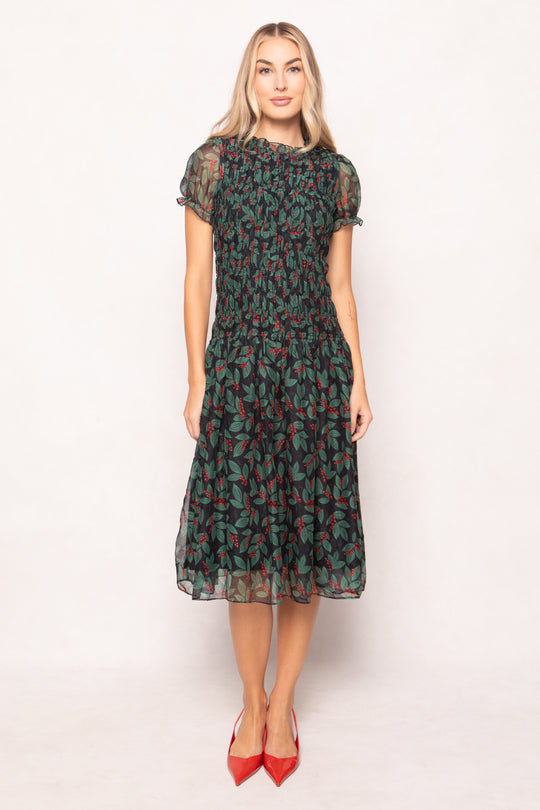 model in green holly berry dress on a white backdrop