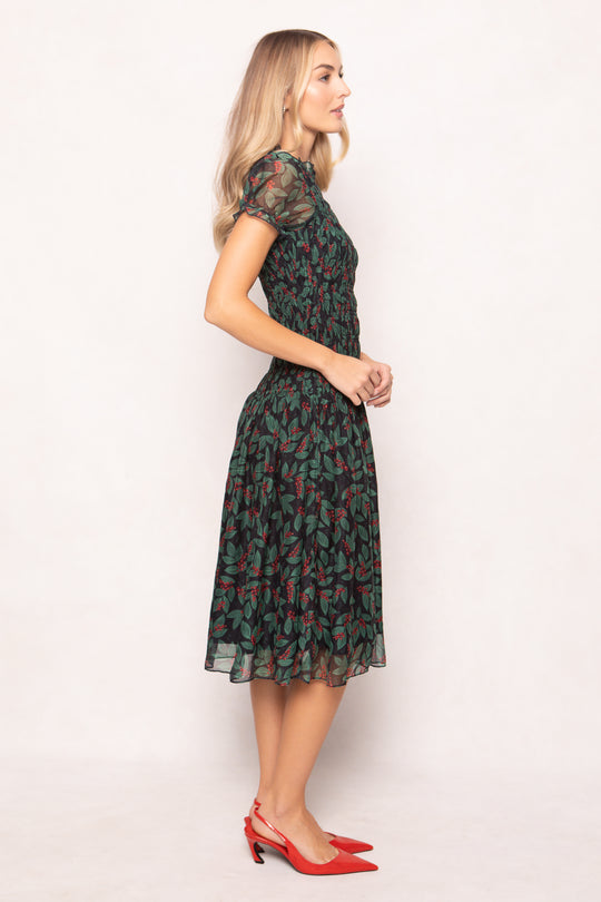 model in green holly berry dress on a white backdrop