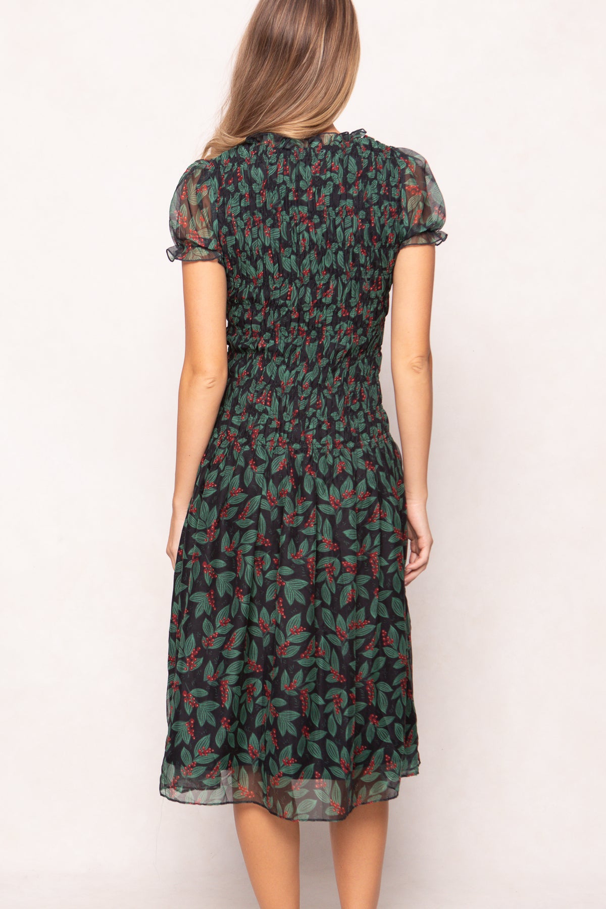 model in green holly berry dress on a white backdrop