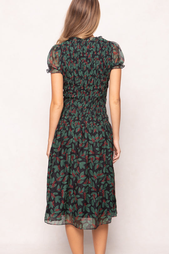 model in green holly berry dress on a white backdrop