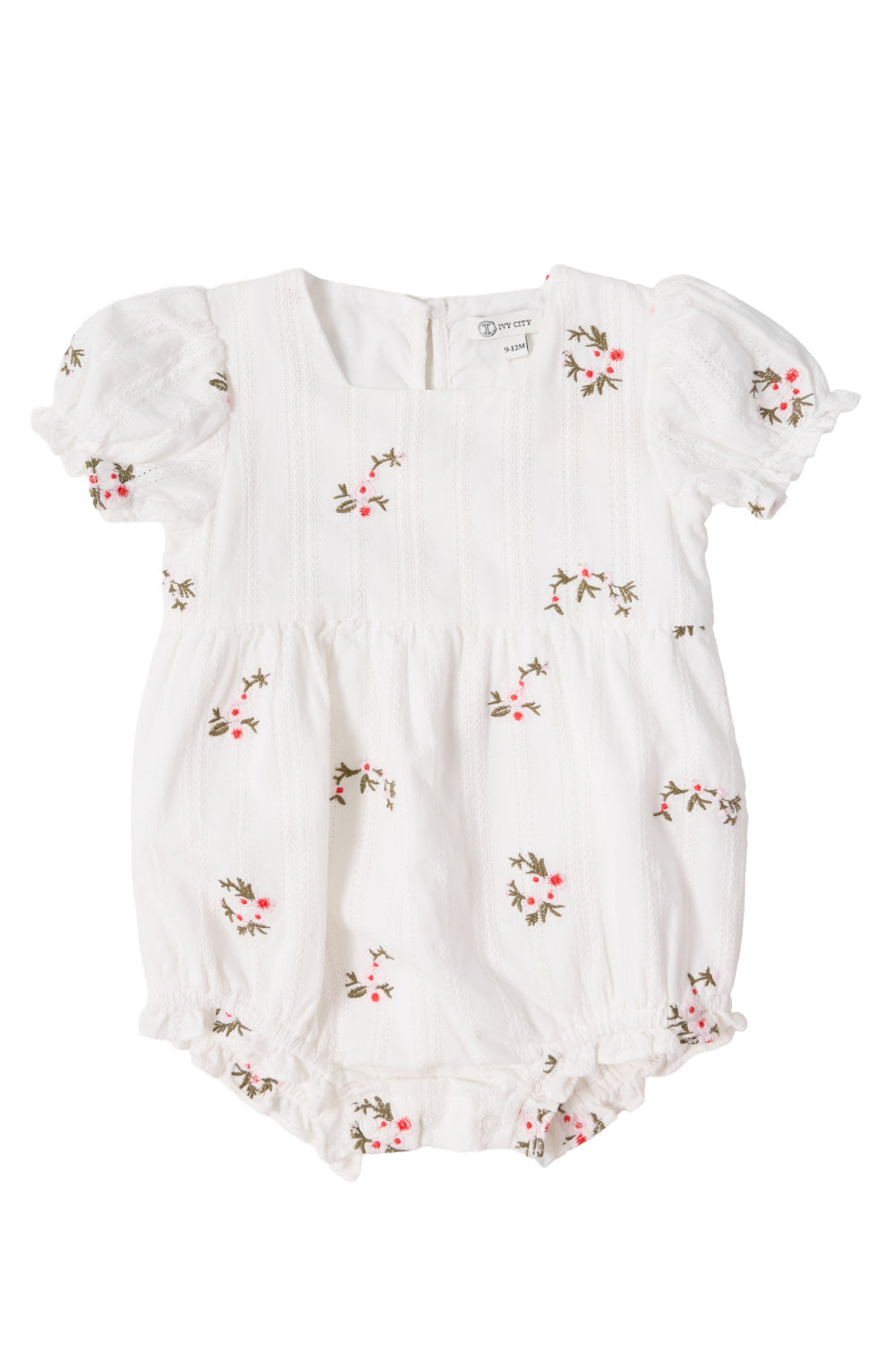 Dress your little one in the Baby Jessie Romper in Ditsy Embroidery by Ivy City Co. This white romper features short puff sleeves, subtle vertical stripes, and a charming embroidered pattern of small pink and green flowers. The smocked bodice lends classic detail, while elastic leg openings and sweet ruffles provide a soft, adorable touch. Made from comfortable embroidered cotton and photographed on a plain background for a clear view of its delightful design.