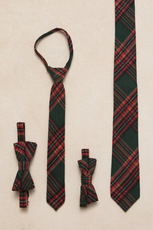 A set of green plaid ties in various styles including a necktie, bow tie, and pre-tied versions, displayed against a neutral background.