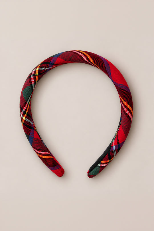 A Hair Bow in Holiday Plaid by Ivy City Co, featuring red, green, yellow, and black tartan cotton flannel fabric, is showcased on a plain beige background.