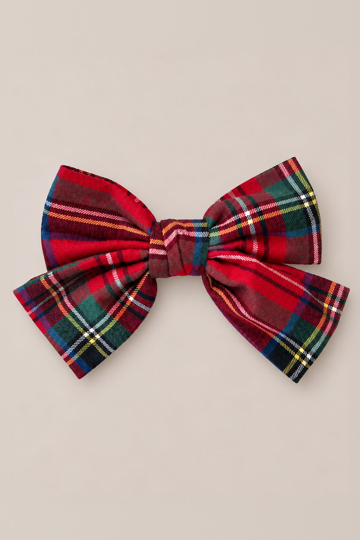 The Hair Bows in Holiday Plaid by Ivy City Co are shown on a plain light beige background. These bows feature a festive red and green tartan pattern with yellow and white stripes, crafted from soft cotton flannel. Tied neatly with symmetrical loops and tails, they make the perfect holiday accessory or a charming accent for your favorite plaid headband.