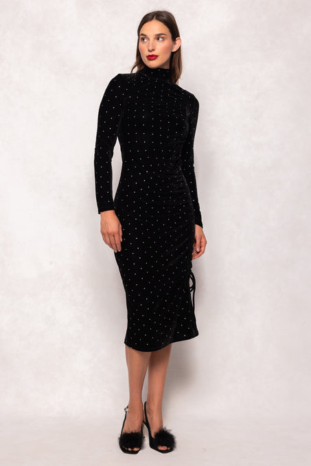 Woman wearing a black dress with white polka dots against a plain background