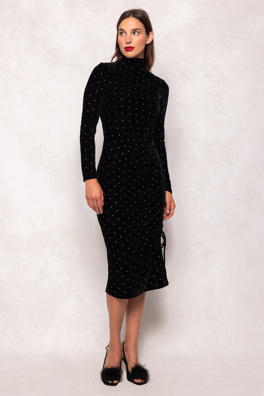 Woman wearing a black dress with white polka dots against a plain background