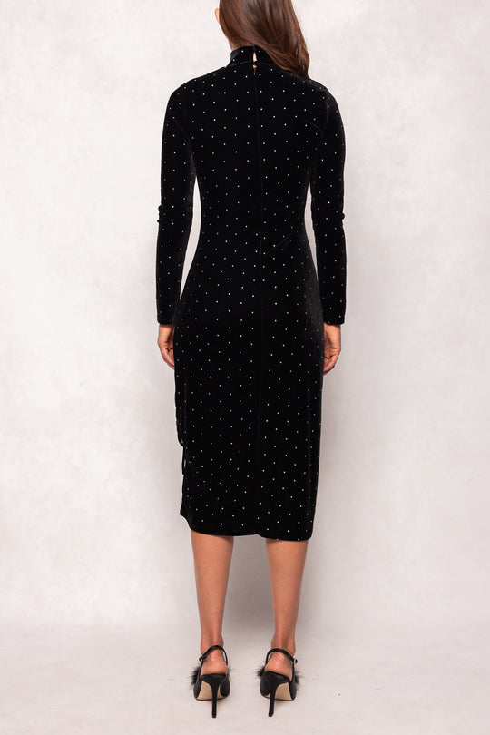 Black dress with white polka dots worn by a person on a white background