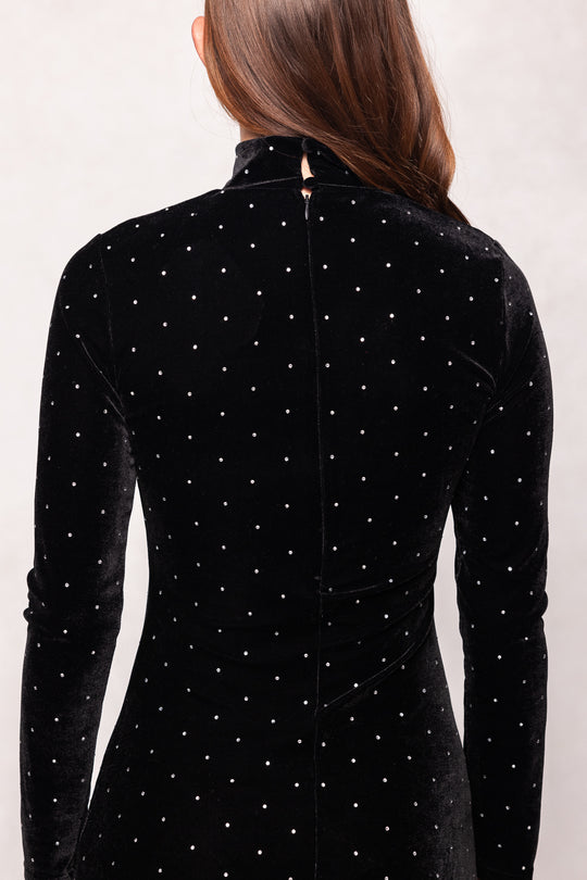 Black velvet dress with white polka dots worn by a person on a plain background