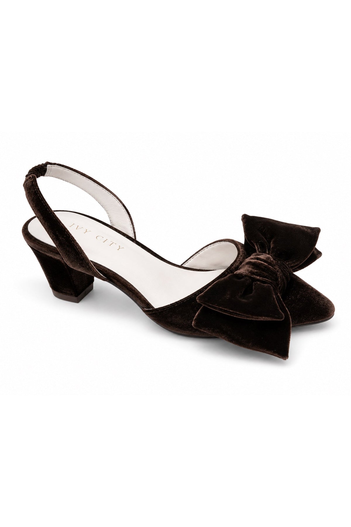 The Eloise Bow Heel in Brown by Ivy City Co is a brown velvet slingback shoe with a mid-height block heel and a large decorative bow on the front, featuring a comfortable leather insole, shown against a white background.