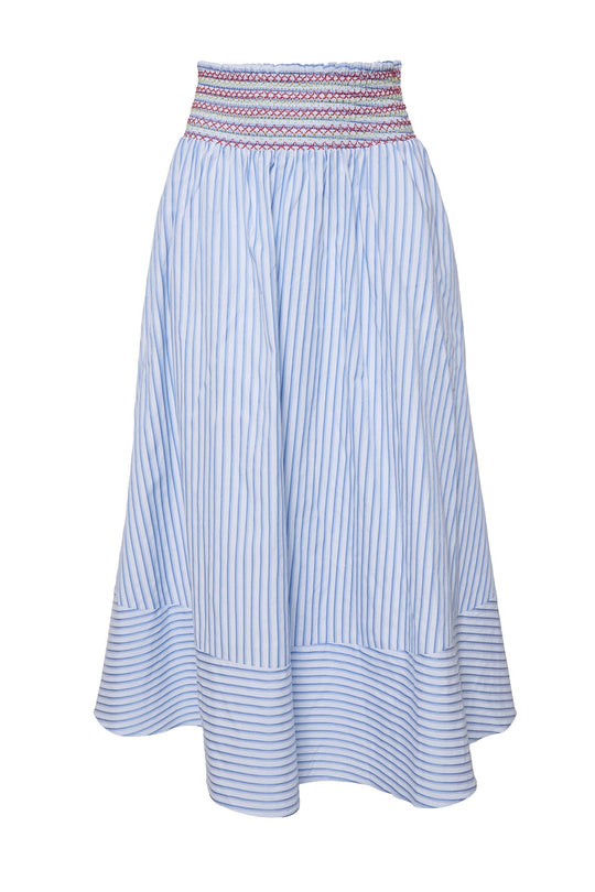 The Bluebell Skirt in Blue & White Stripes by Ivy City Co features light blue and white stripes, a flared hem, and a wide smocked waistband with red and blue stitching. This stylish skirt offers comfort and is maternity-friendly, making it a versatile addition to any wardrobe.