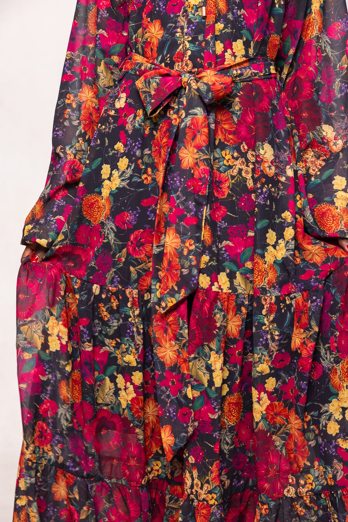 Close-up of the Ivy City Co Imogen Dress in Night Garden: a long sleeve floral maxi dress with a tied waist, featuring vibrant red, yellow, orange, and green hues—ideal for fall or as a maternity-friendly option.