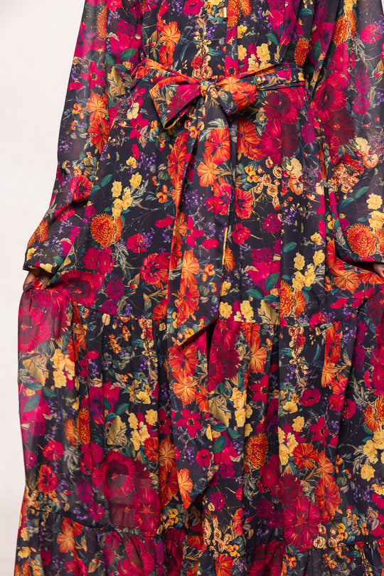 Close-up of the Ivy City Co Imogen Dress in Night Garden: a long sleeve floral maxi dress with a tied waist, featuring vibrant red, yellow, orange, and green hues—ideal for fall or as a maternity-friendly option.