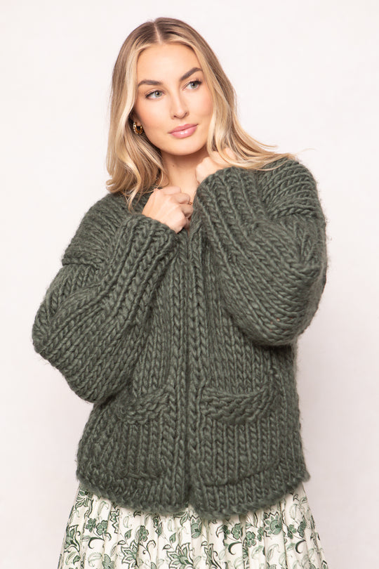 Woman wearing a green knitted sweater against a plain background