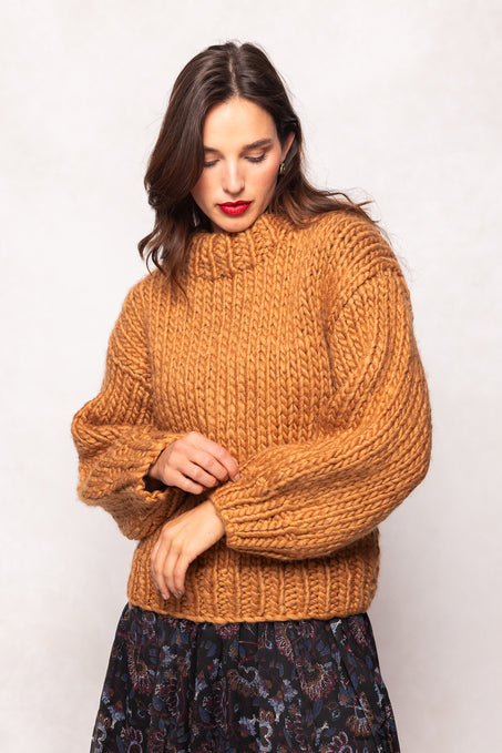 Woman wearing a mustard yellow sweater against a white background