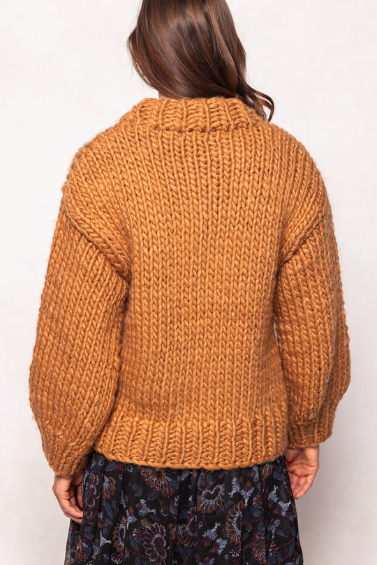 Person wearing a mustard yellow knitted sweater on a white background