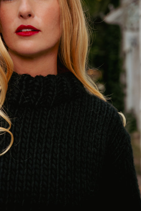 Woman wearing a black knitted sweater with a blurred background
