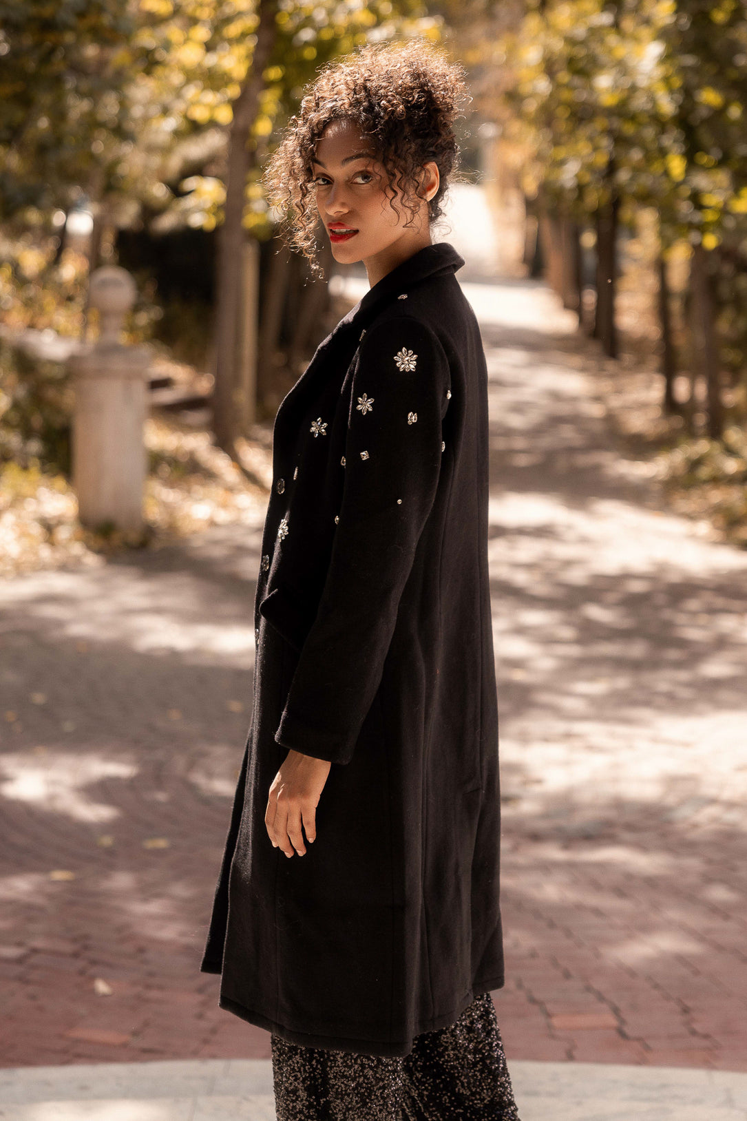 Woman wearing a black coat with star patterns in an outdoor setting