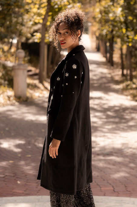 Woman wearing a black coat with star patterns in an outdoor setting