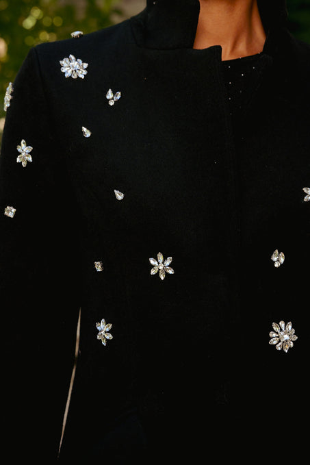 Black coat with floral embellishments on a blurred background
