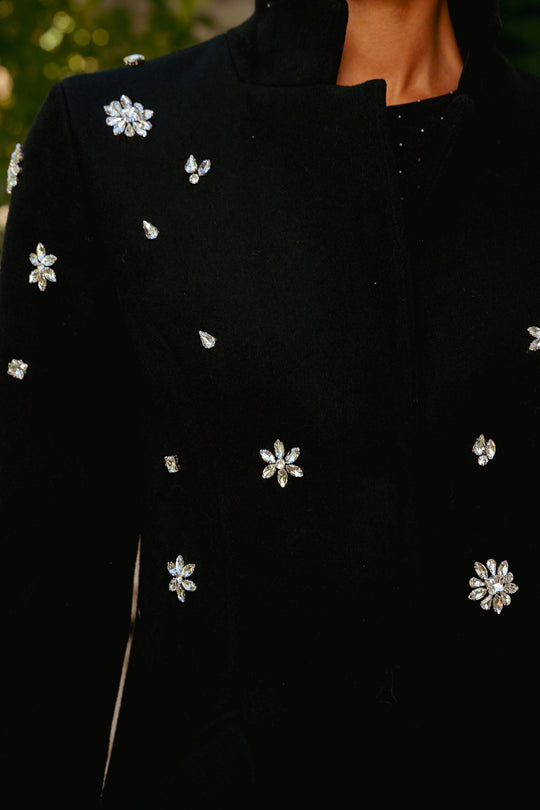 Black coat with floral embellishments on a blurred background
