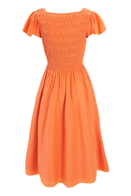 The Janessa Dress in Orange by Ivy City Co features a smocked, fitted bodice, flared skirt, ruffled sleeves, and gathered waist for a comfortable summer look.
