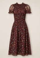 The Jennifer Dress in Aubergine Elysian Vine by Ivy City Co is a midi dress featuring a smocked bodice, puff sleeves with ruffle trim, and a flared skirt adorned with multicolor ditsy floral print on sheer fabric. Maternity friendly and effortlessly stylish, it provides both comfort and charm for any occasion.