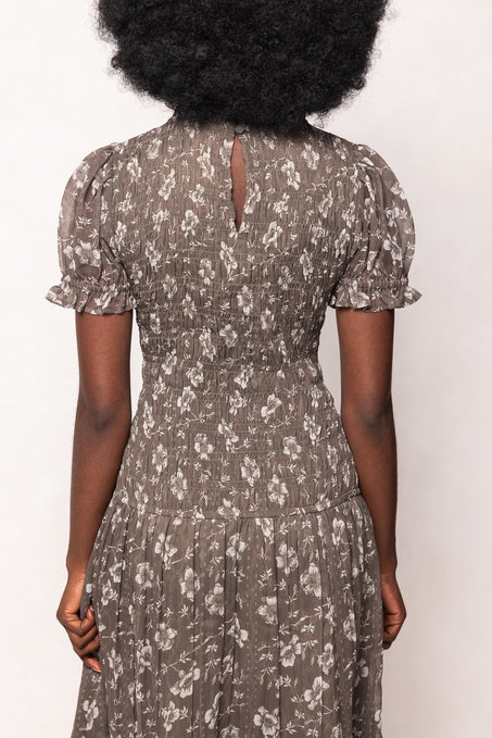 Person wearing a floral dress with short sleeves against a white background