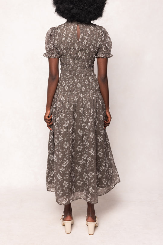 Woman wearing a floral dress with puffed sleeves on a white background