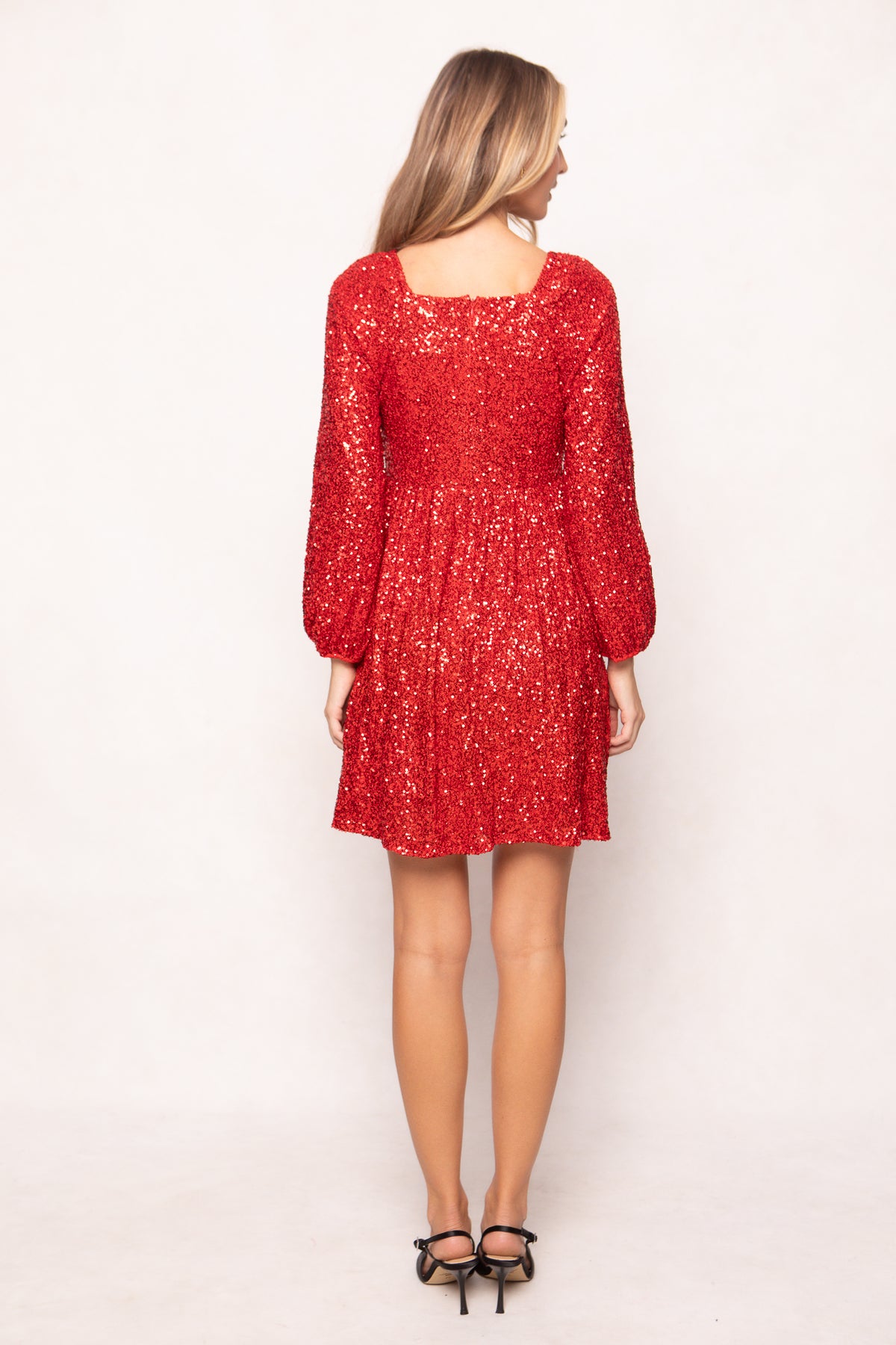 Woman wearing a red dress with long sleeves on a white background