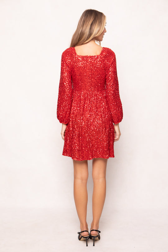 Woman wearing a red dress with long sleeves on a white background