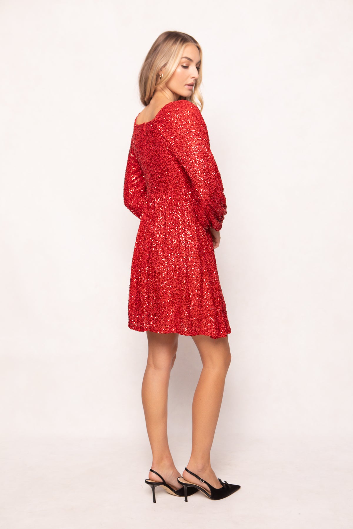 Woman wearing a red sequin dress against a white background