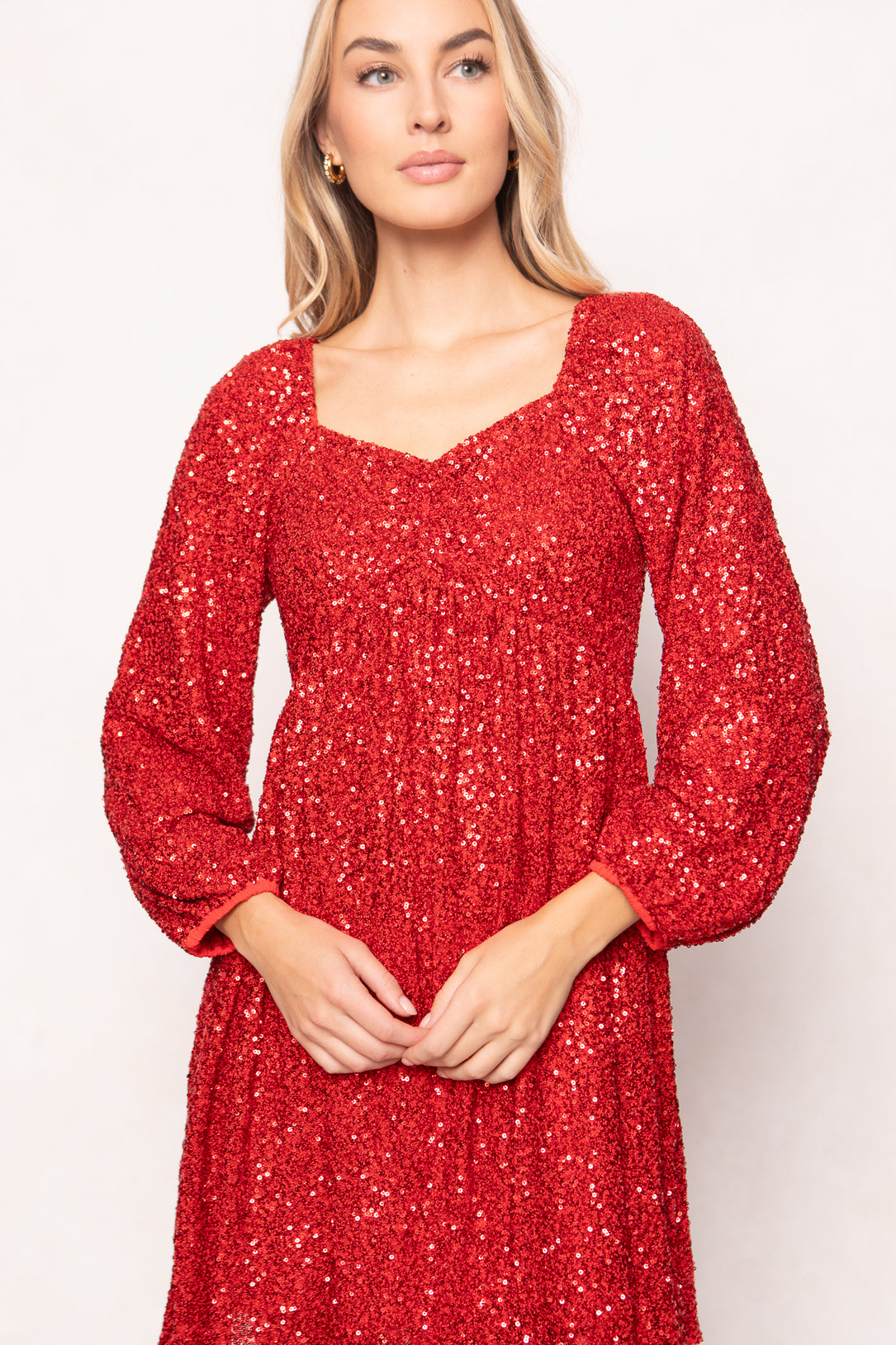 Woman wearing a red sequin dress against a white background
