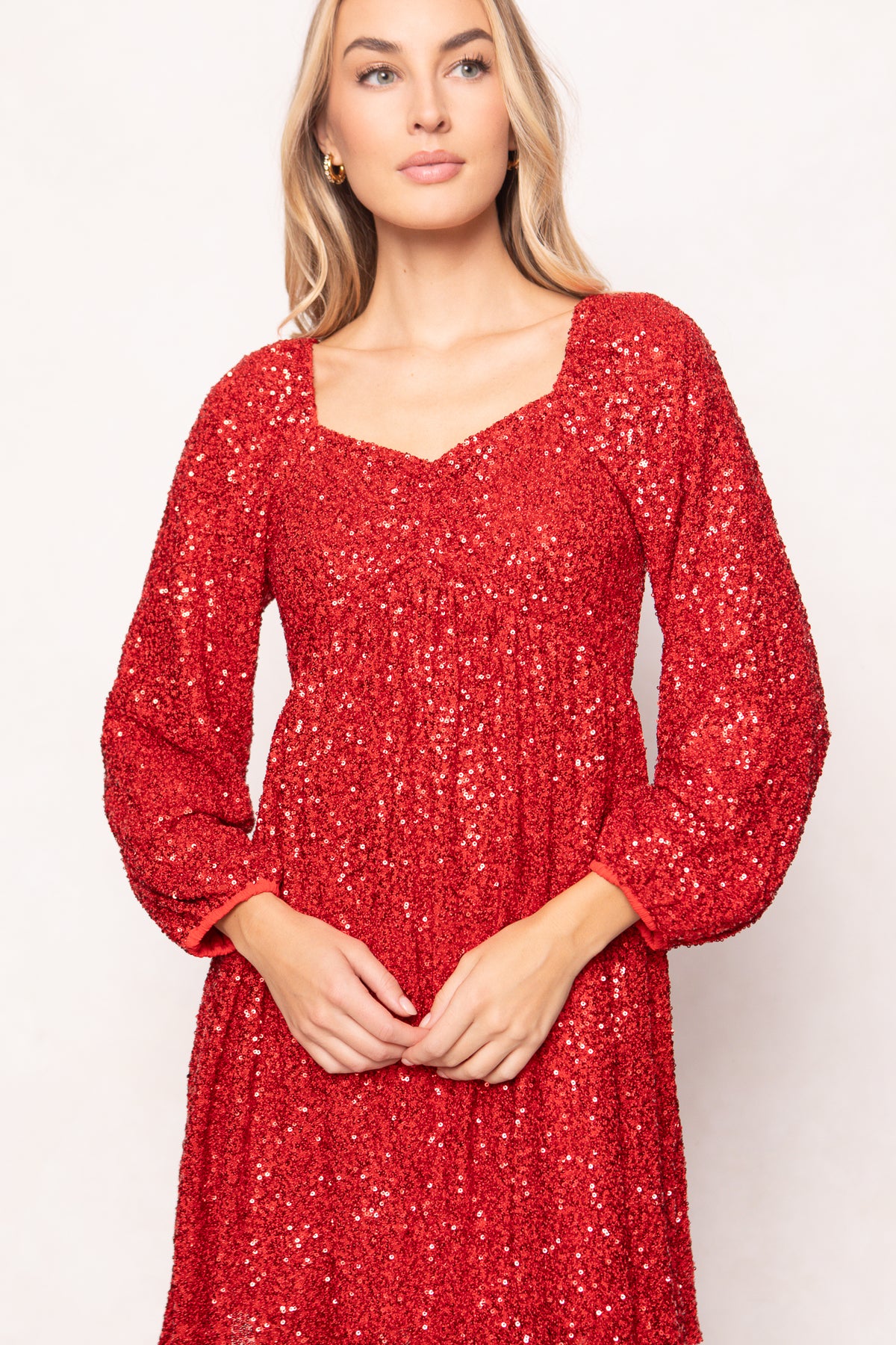 Woman wearing a red sequin dress against a white background