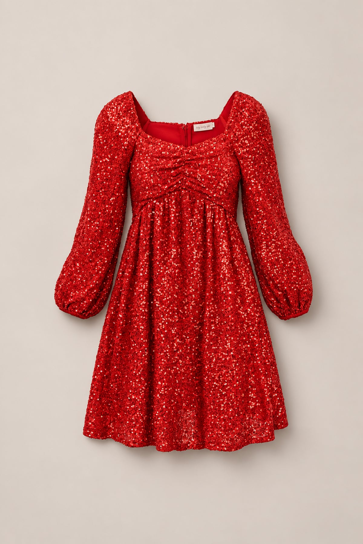 The Jewel Dress in Red Sequin by Ivy City Co features long, puffed sleeves, a gathered bust, and a flattering sweetheart neckline. This stunning dress is displayed on a plain light background.