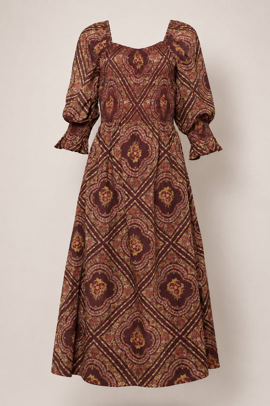 The Josephine Dress in Nocturne Diamond Rose by Ivy City Co features a vintage-inspired, long silhouette with three-quarter puff sleeves and an ornate burgundy and gold diamond pattern, displayed on a neutral background.